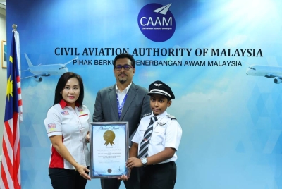 Norazman (tengah) menyaksikan penyampaian sijil anugerah 'Malaysia Book of Record 2023: Most Aviation Ambassador Awards Obtain By A Child' oleh Poi Leng (kiri) kepada Sarvysswharrann di Podium B CAAM pada Selasa. - Foto Bernama