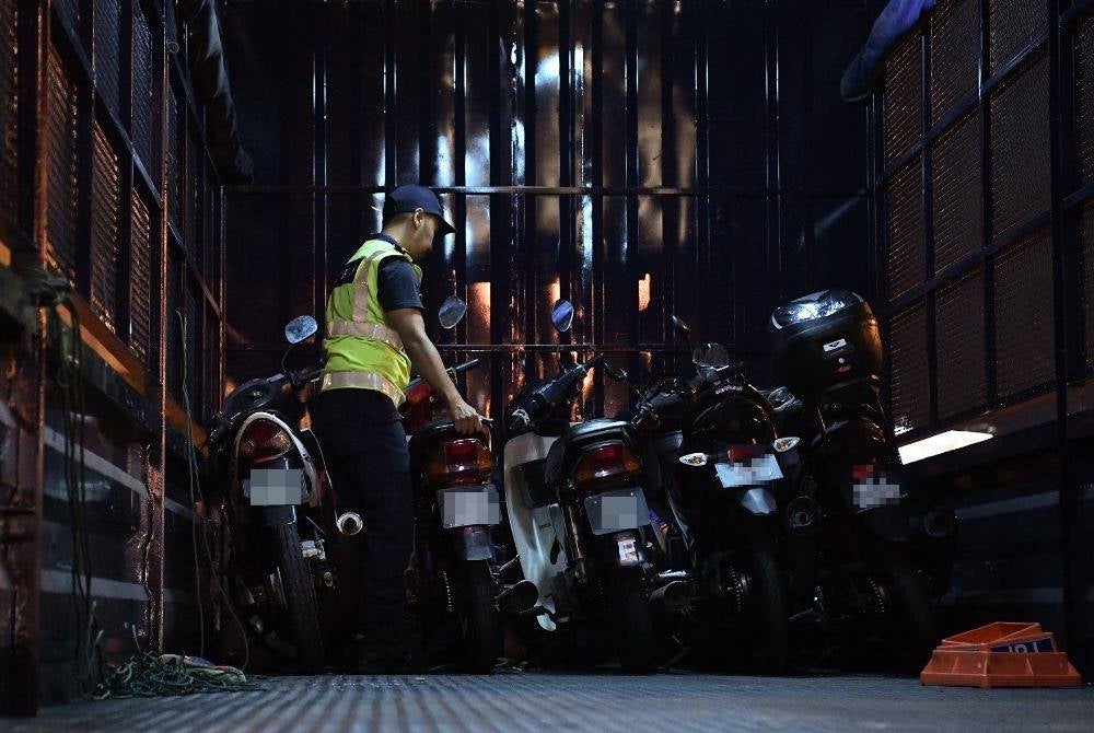 Pegawai Jabatan Pengangkutan Jalan menyusun motor yang disita ke dalam sebuah lori pada Operasi Hari Raya Aidiladha 2023 Peringkat Selangor di Plaza Tol Petaling Jaya Selatan pada malam Selasa. - Foto: Bernama