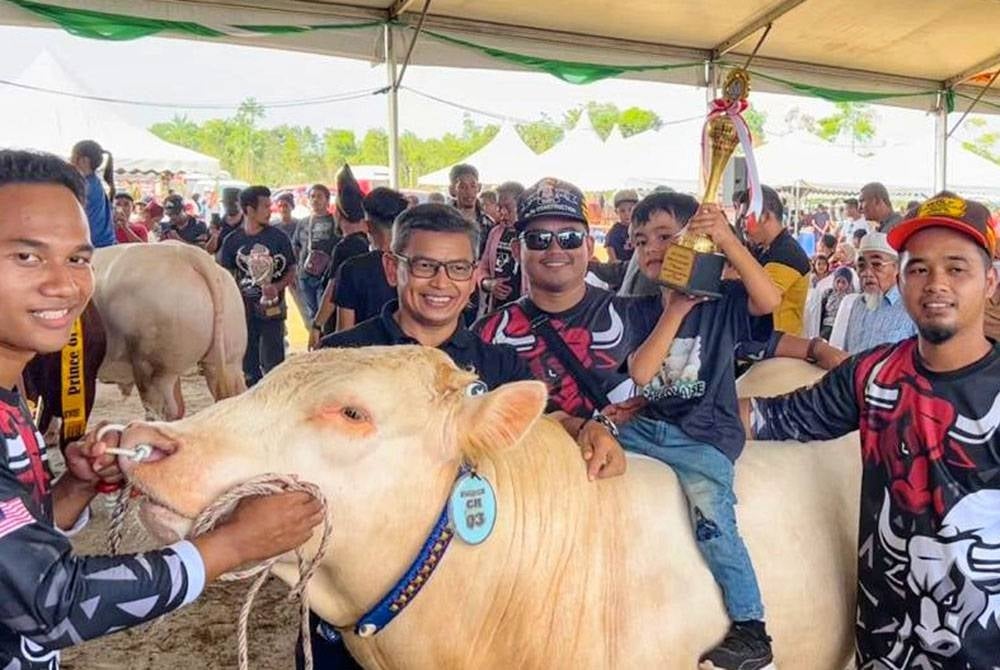 Nik Mohamad Salahudin (tiga dari kiri) bersama dua adiknya merakam gambar bersama Exco Pertanian, Industri Makanan, Perladangan, Komoditi dan Pembangunan Luar Bandar Terengganu, Dr Azman Ibrahim (dua dari kiri) ketika Himpunan Lembu Sado Pantai Timur 2022 di Jabi, Besut.
