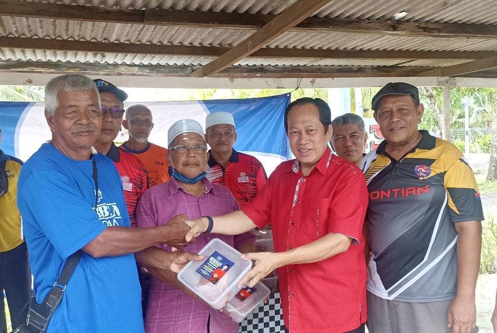 Ahmad ( tengah) menyerahkan daging korban kepada penduduk Kampung Parit Ibrahim pada Jumaat.