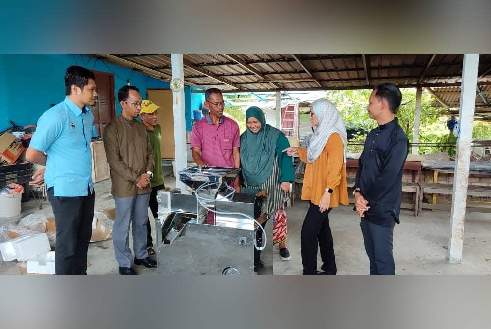 Nor Azmi (tiga kiri) dan isteri (empat kiri) ketika menerima mesin perah santan daripada Pejabat daerah Jelebu baru-baru ini.