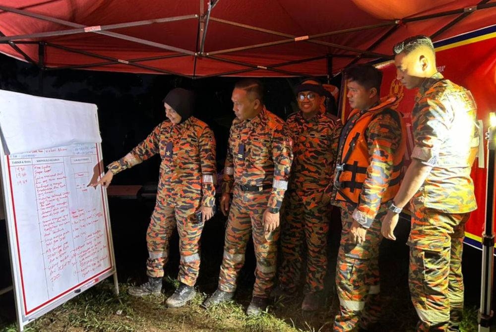 Nazah (kiri) memberi maklumat kepada pegawai dan anggota bomba ketika operasi menyelamat.