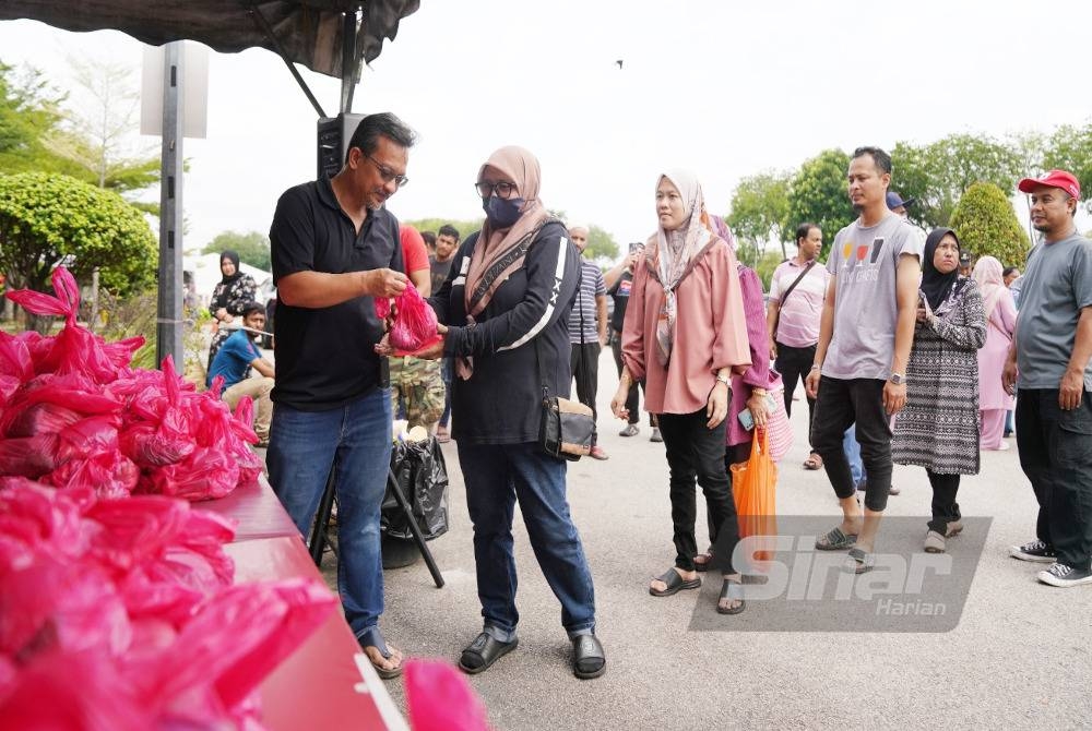 Akmal Eirfan mengagihkan daging kepada petugas yang hadir. - FOTO ROSLI TALIB