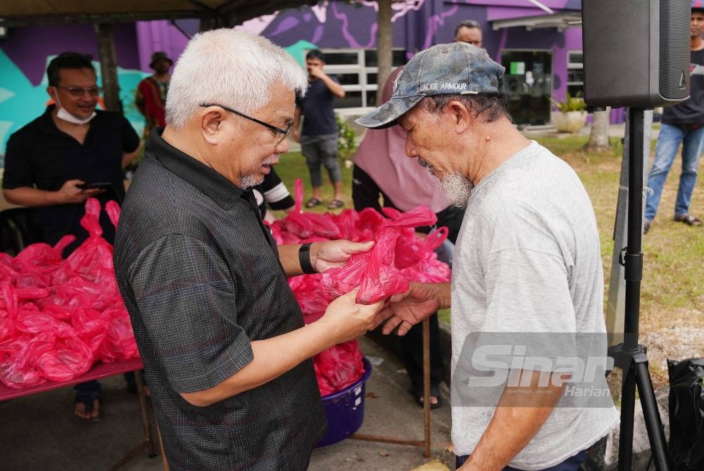 Hussamuddin turut bersama menyerahkan agihan daging kepada petugas dan kakitangan yang hadir. - FOTO ROSLI TALIB