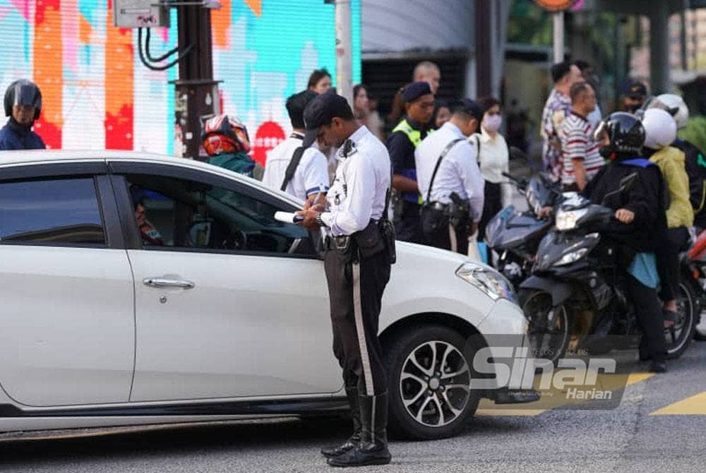 Anggota polis mengenakan saman kepada pesalah lalu lintas semasa Operasi Hormat Undang-Undang Jalan Raya Polis Kuala Lumpur dilakukan di Kuala Lumpur pada Isnin. Foto: SINAR HARIAN/Rosli Talib.