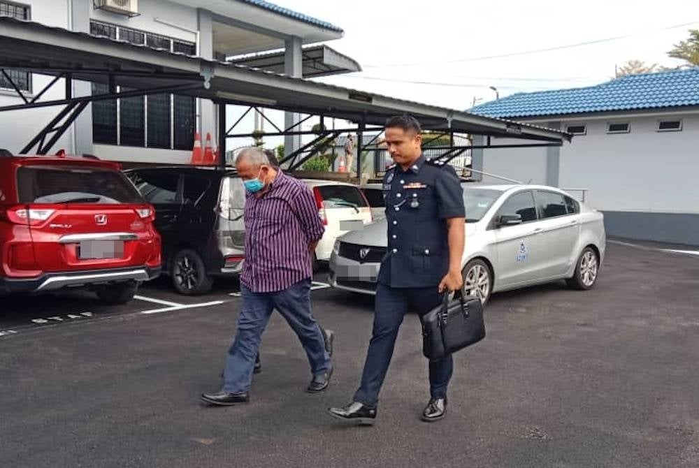 Tertuduh ketika diringi pegawai polis sebaik tiba di pekarangan mahkamah pada Selasa.
