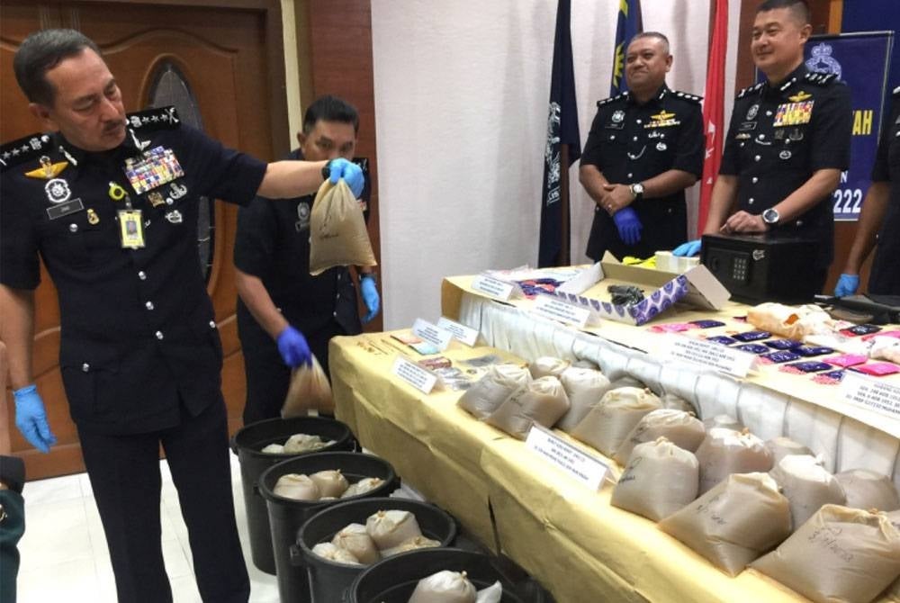 Muhamad Zaki (kiri) menunjukkan rampasan air ketum dalam bungkusan dalam Op Tapis Khas dan Op Tapis Bersepadu.