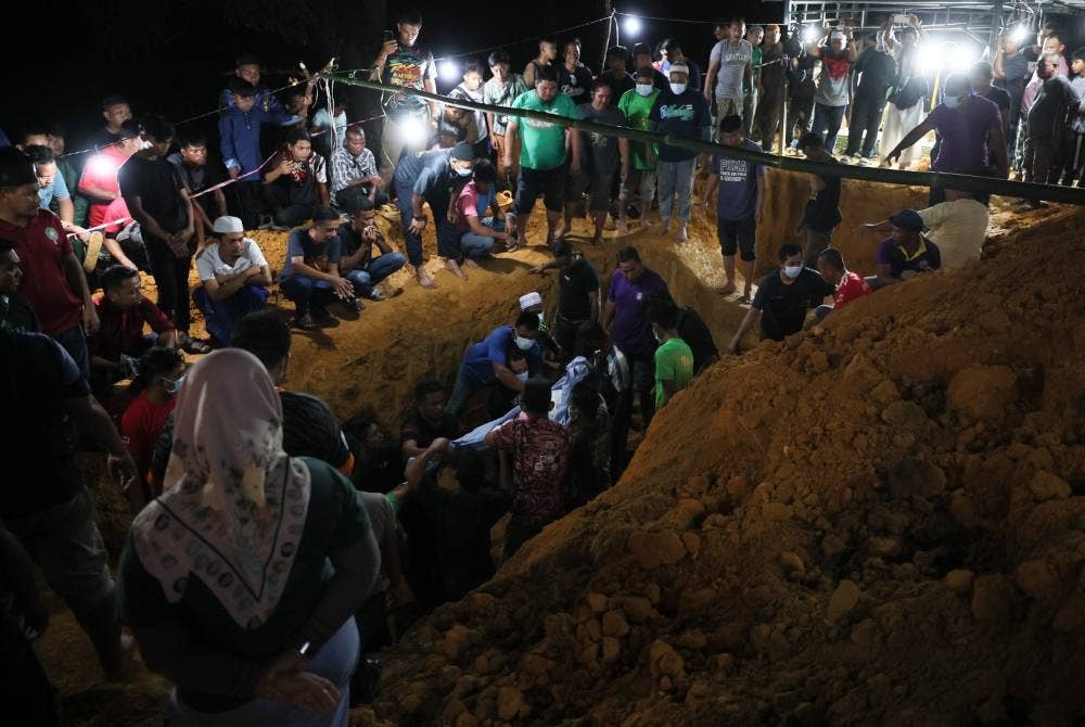 Jenazah tujuh daripada sembilan sekeluarga yang meninggal dunia dalam tragedi kepala air di Jeram Air Putih selamat dikebumikan dalam satu liang lahad di Tanah Perkuburan Islam Felda Lebar Hilir 3 malam tadi. - Foto Bernama