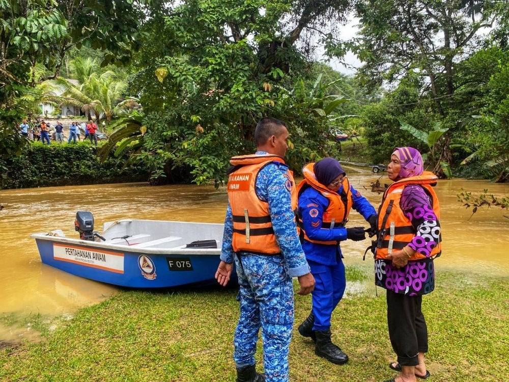 Anggota APM Jerantut bantu pindahkan mangsa di Kampung Sempadan. - Foto ihsan Sekretariat Jawatankuasa Bencana Daerah 