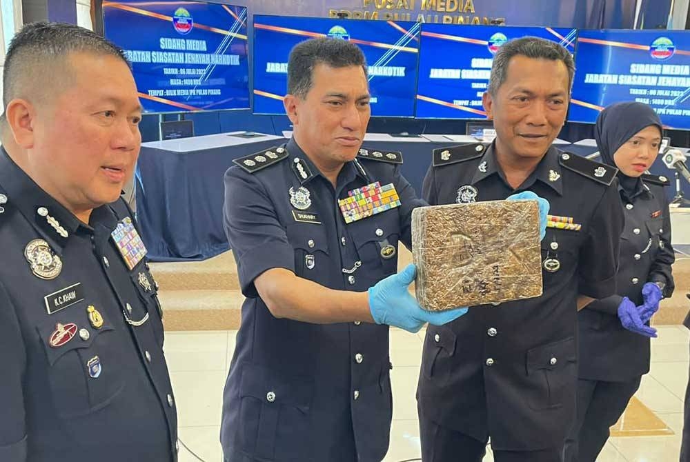 Kok Chin (kiri) dan Ketua Jabatan Siasatan Jenayah Narkotik Pulau Pinang, Asisten Komisioner Mohd Shukhairy Abd Sabhe menunjukkan ganja yang dirampas bersama suspek.