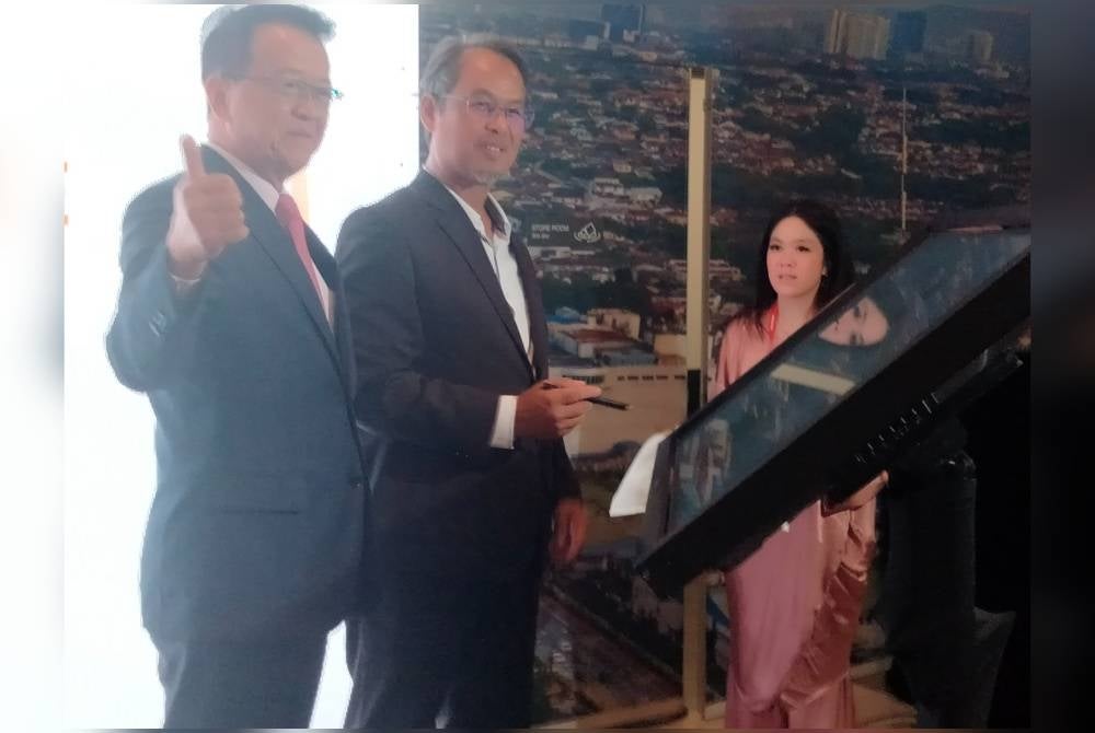 Jeffrey (kiri) mengiringi Mohamad Azhan menandatangani plak perasmian.