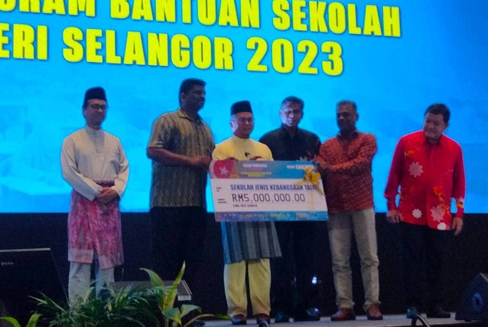Amirudin (tiga dari kiri) menyampaikan replika cek kepada wakil penerima pada Majlis Penyerahan Program Bantuan Sekolah Negeri Selangor 2023.