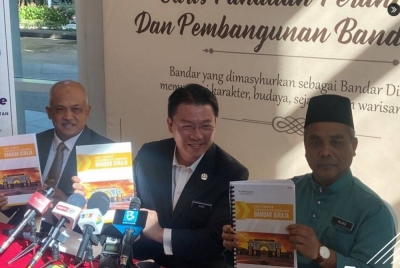 Kor Ming menunjukkan buku Garis Panduan Perancangan dan Pembangunan (GPP) Bandar Diraja yang diperkenal KPKT di Putrajaya. - Foto Twitter Bernama