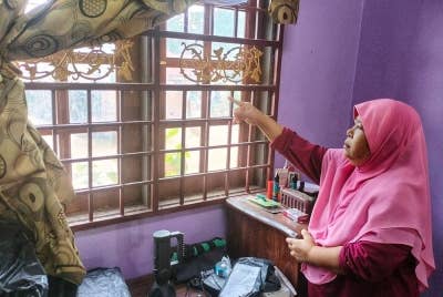Mahani menunjukkan tingkap yang diumpil oleh pencuri menyebabkan duit tabung milik anaknya hilang sebanyak RM1,500