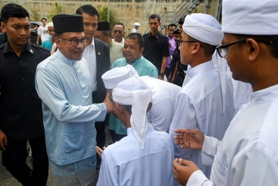 Anwar (dua dari kiri) bersalaman dengan pelajar tahfiz ketika hadir ke Masjid Kariah Panchor Jaya bagi menunaikan solat Jumaat pada Jumaat. - Foto: Bernama