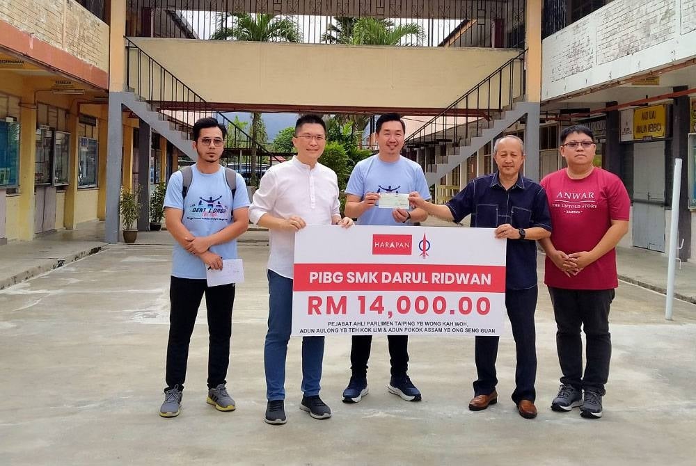 Kah Woh (dua dari kiri) menyampaikan replika sumbangan RM14,000 kepada Pengetua SMK Darul Ridwan, Mohd Makri Jafar (dua dari kanan) ketika melawat sekolah berkenaan.