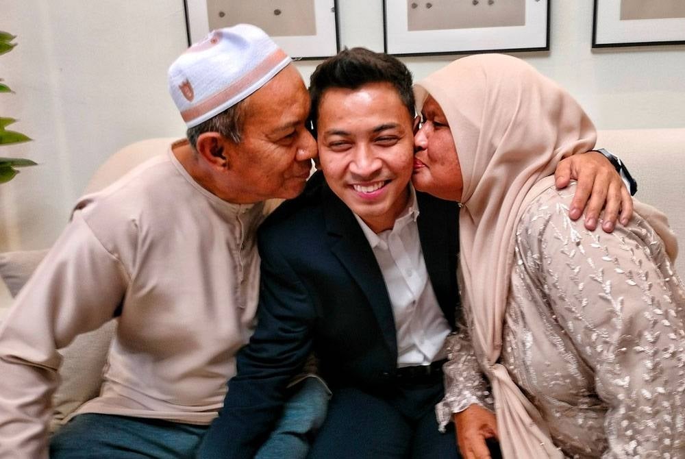 Muhammad Hilman (tengah) dicium ibu bapanya.