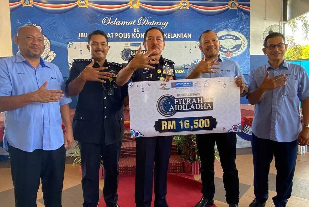 Muhamad Zaki (tengah) menerima replika cek yang disampaikan oleh Mohamed Al Namiri (dua, kanan) semasa Program Fitrah Aidiladha Bank Rakyat di Kota Bharu pada Ahad.