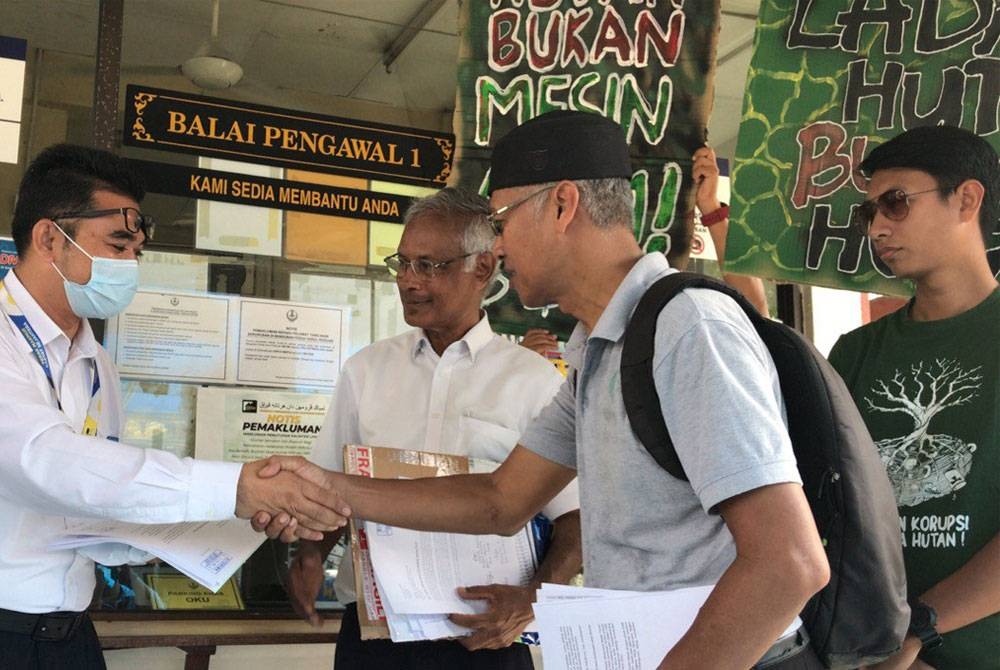 Rahim (kiri) mewakili pejabat Menteri Besar Perak menerima memorandum yang diserahkan Meor Razak (dua dari kanan) bagi Hentikan Projek Ladang Hutan di Hutan Kledang Saiong.