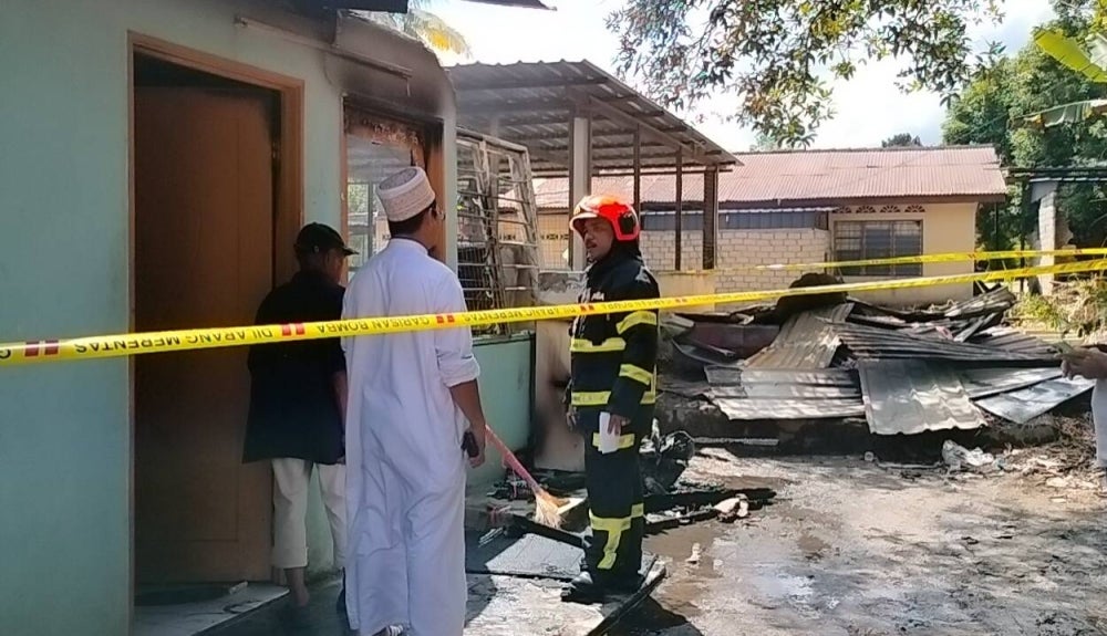 Mohd Zamri (tiga dari kiri) ketika melihat keadaan bangunan madrasah tahfiz yang terbakar.