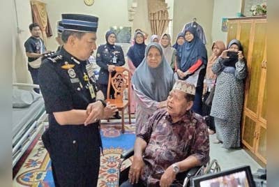 Muhamad Zaki (kiri) bertanya khabar Yusof pada Majlis Penyampaian Pingat Jasa Pahlawan Negara Tanpa Istiadat dan Penyerahan Sumbangan Katil Kepada Pesara Polis Sakit Kronik, pada Isnin.