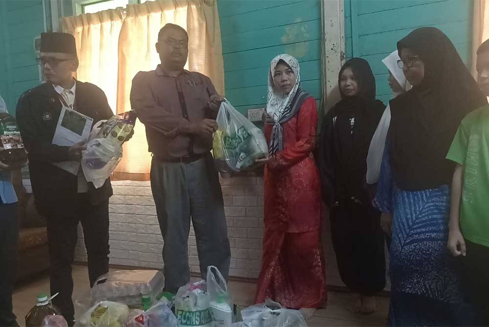 Mas Imran menyerahkan sumbangan kepada Maznah di Kampung Melayu Majidee pada Selasa.