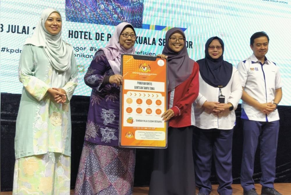 Fuziah (dua dari kiri) menyerahkan simbolik Program Rintis Bantuan Tanpa Tunai kepada salah seorang penerima pada Program Outreach Sara Hidup dan Aduan Suri di Hotel De Palma pada Khamis.