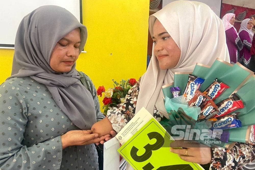 Rorida (kiri) bangga dengan kejayaan Nurulain yang kudung tangan kanan sejak lahir.