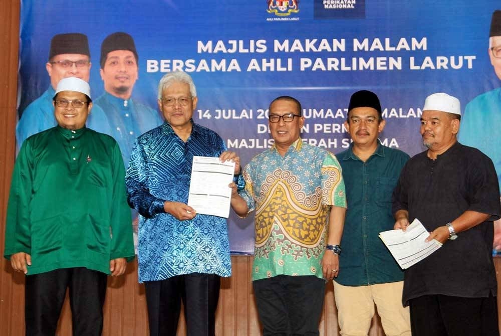 Hamzah (dua dari kiri) menerima borang kemasukan ahli Bersatu daripada bekas Ketua UMNO Bahagian Larut, Datuk Faizul Arby Mohd Shohor (tengah) dan bekas Ketua UMNO Cawangan Batu 6, Sayuti Husin (kanan).