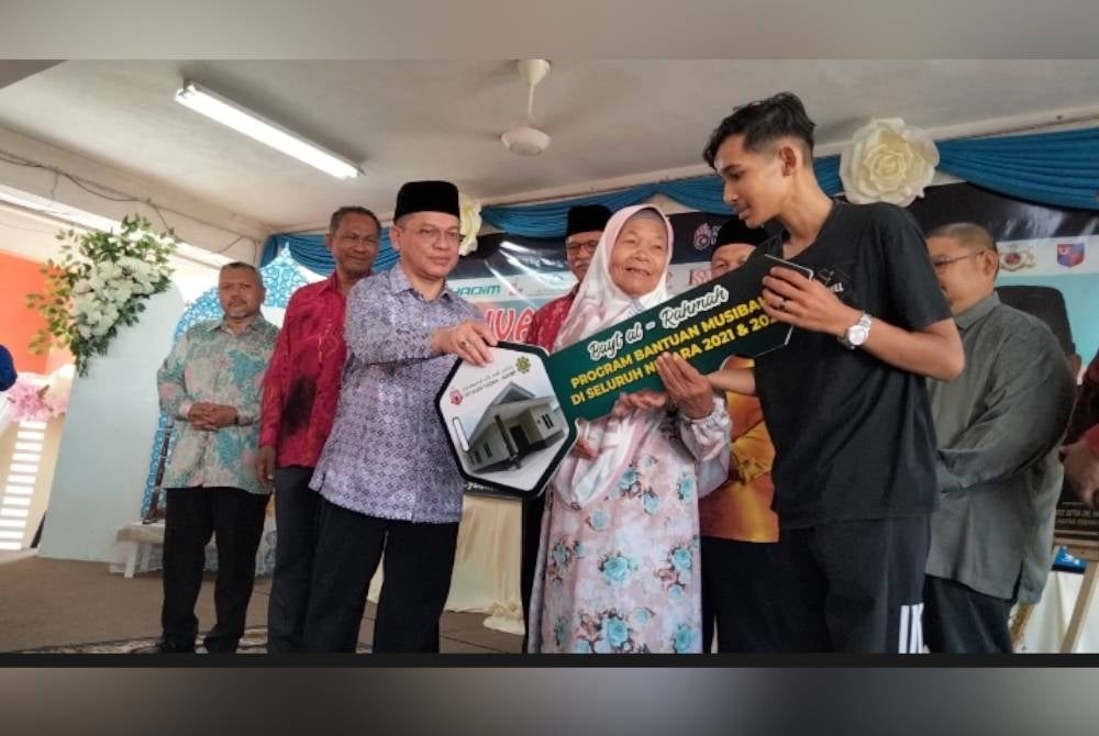 Dr Mohd Na'im (depan, kiri) menyampaikan kunci rumah kepada penerima bantuan musibah ketika Karnival Al-Falah Peringkat Negeri Kelantan di sini pada Sabtu.