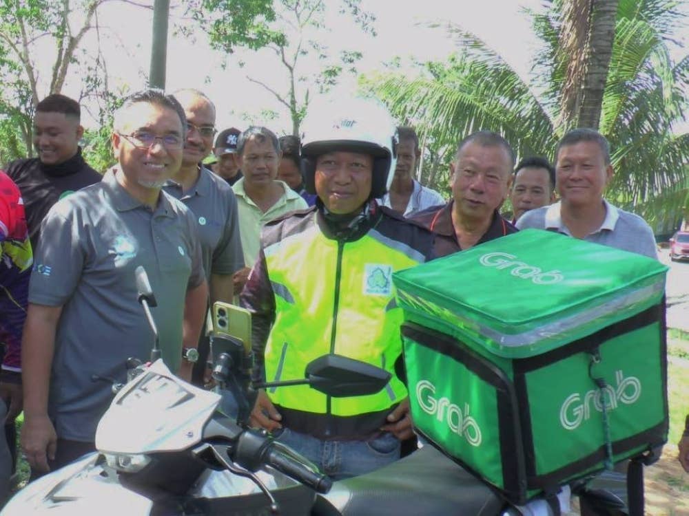 Adly (kiri) bersama salah seorang penunggang p-hailing yang menyertai
menyertai Skim Keselamatan Sosial Pekerjaan Sendiri (SKSPS) di Felda Tun Ghafar, Alor Gajah pada Sabtu.