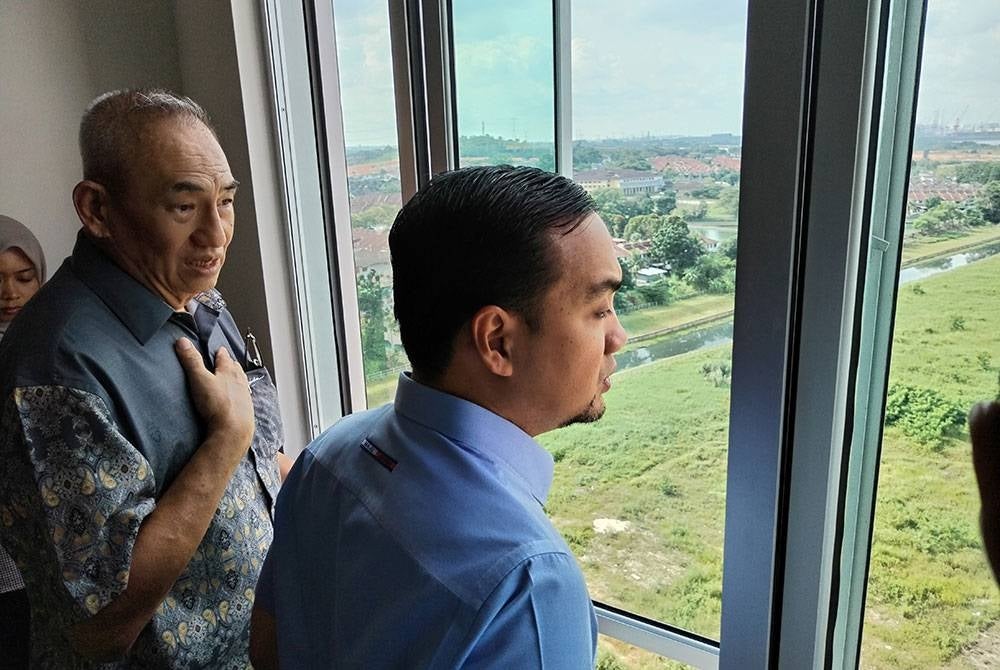 Onn Hafiz (kanan) memerhatikan kawasan sekitar Pangsapuri Senibong Indah dari salah satu unit di tingkat 13.