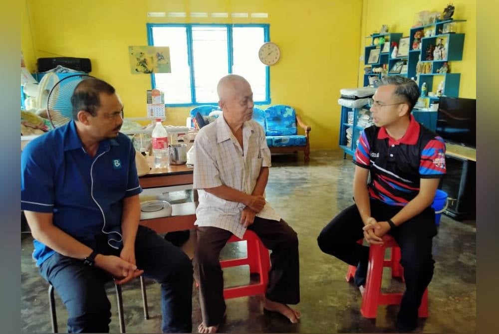 Fahmi (kanan) melawat wartawan sambilan akhbar bahasa Cina, Ng Kan Seng, 68, di rumahnya di Mambang Di Awan, Kampar pada Ahad.