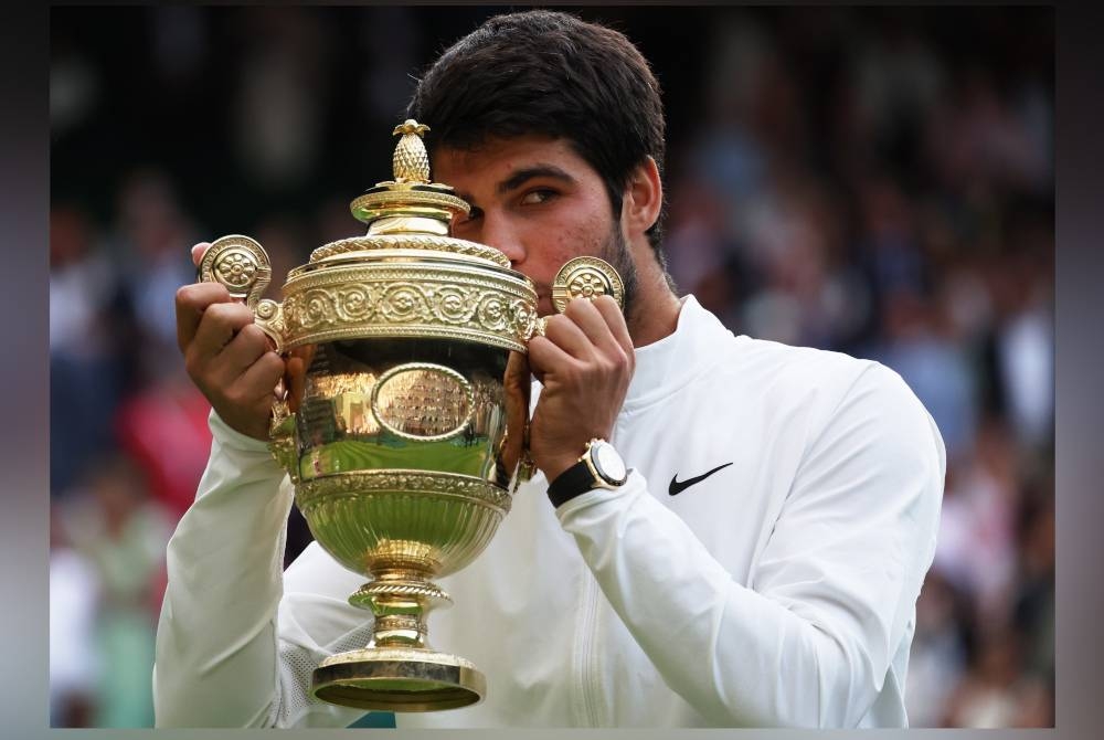 Alcaraz mengucup trofi selepas mengungguli kejohanan tenis Wimbledon menewaskan Djokovic di Britain awal pagi Isnin. - Foto EPA