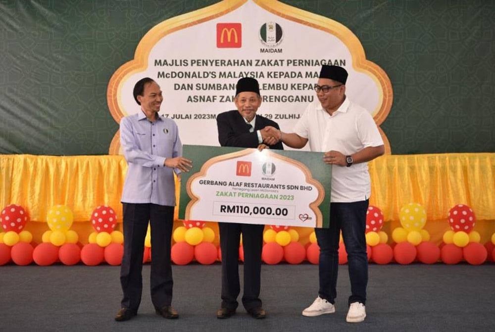 Shaikh Harun (tengah) menerima replika cek zakat perniagaan bernilai RM110,000 daripada Shadan (kanan) pada Majlis Penyerahan Zakat Perniagaan dan Sumbangan Lembu oleh McDonald's Malaysia kepada asnaf zakat negeri Terengganu pada Isnin.