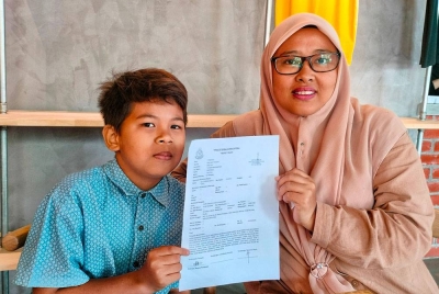 Nor Shahilah (kanan) bersama Nur Muhammad Adam menunjukkan laporan polis yang dibuat Jun lalu bagi melengkapkan proses pengambilan anak angkat.