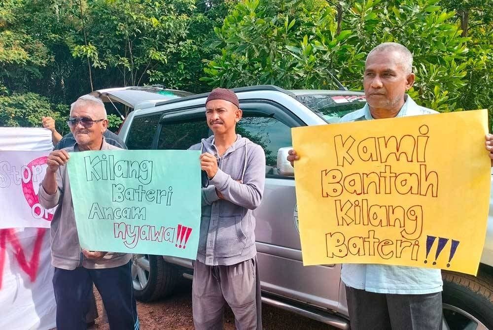 Manan (tengah) bersama penduduk menaik sepanduk ketika himpunan aman bagi membantah pencemaran udara di hadapan pintu masuk sebuah kilang memproses bateri di Bukit Ibam di sini pada Rabu.