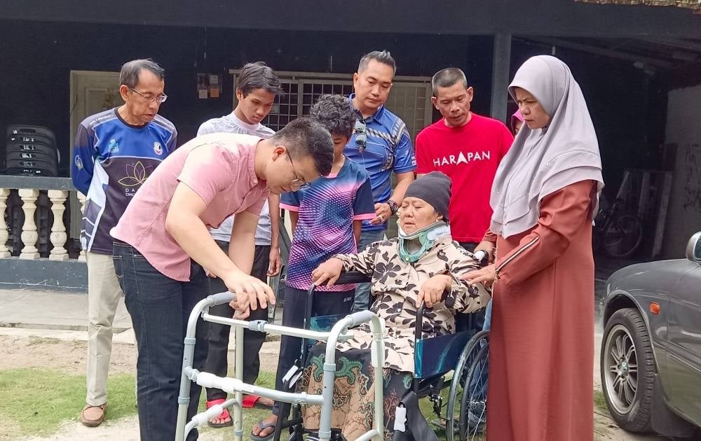 Steven Tiw (kiri) menyerahkan 'walking frame' kepada Noraini bagi membantu proses pemulihan selepas terbabit dalam kemalangan yang turut mengorbankan anak dan menantunya, minggu lalu.