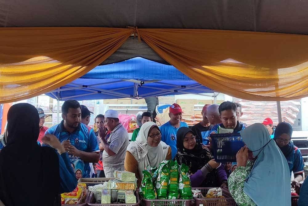 Fuziah (tengah) beramah mesra dengan pengguna yang membeli barangan keperluan pada Program Jualan Rahmah Bergerak DUN Bukit Pinang.
