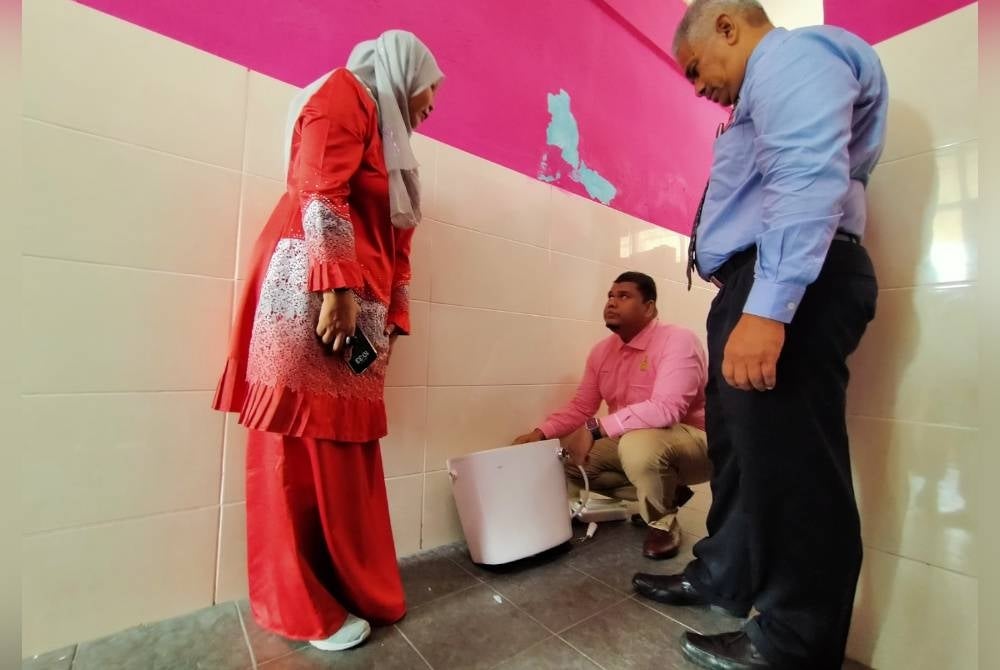 Muhamad Arafat (duduk) melihat tangki pam tandas yang jatuh menimpa murid tersebut Nur Alisha Adawiyah ketika melawat SK Perpaduan di sini pada Jumaat.