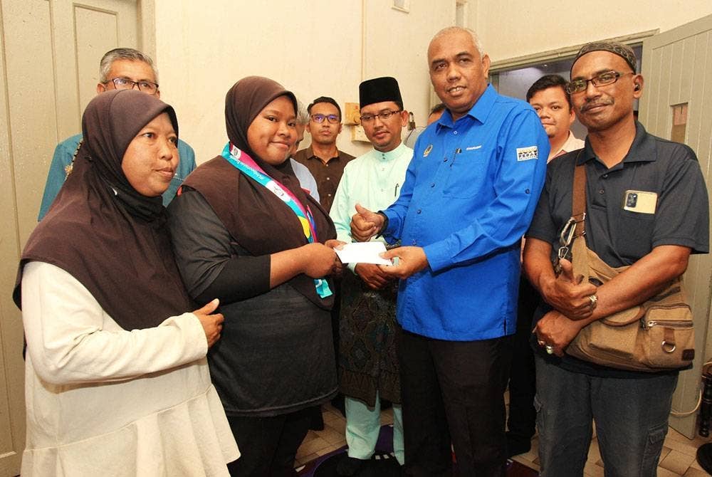 Khairudin menyampaikan insentif daripada kerajaan negeri kepada Nur Asliza. Turut kelihatan ibu bapa Nur Asliza iaitu Mohd Sapri (kanan) dan Asmah (kiri).