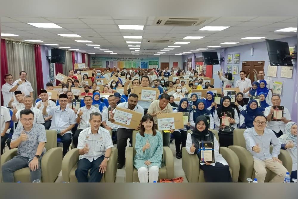 Nie Ching (kiri) menyampaikan sumbangan komputer riba kepada pelajar cemerlang SPM dari Sekolah Menengah Kebangsaan (SMK) Sultan Ibrahim di Pejabat Pendidikan Daerah Kulai, Kulai, pada Sabtu.