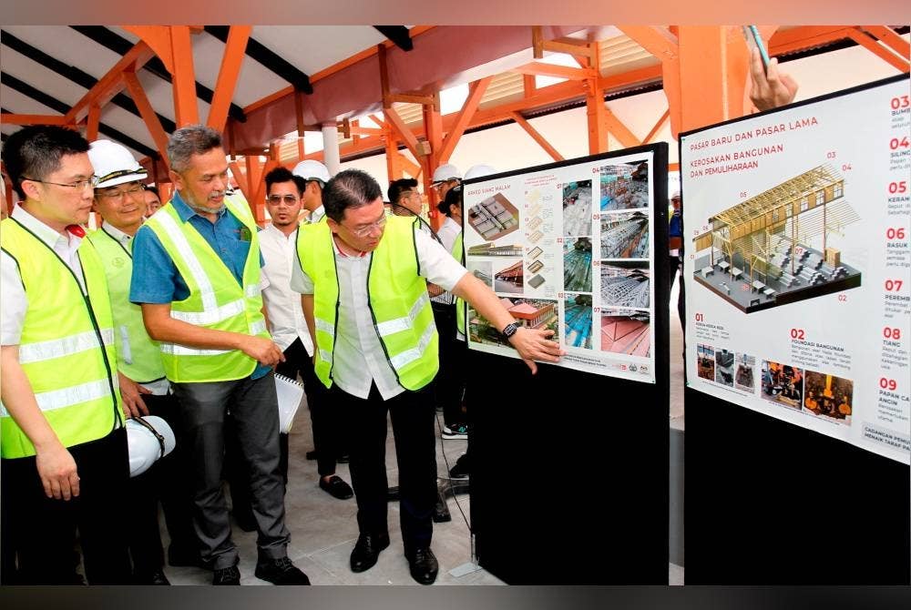 Kor Ming (kanan) melihat dari dekat infografik menaik taraf infrastruktur ketika mengadakan lawatan ke Program Sentuhan Kasih (KPKT) di Pasar Warisan Taiping pada Sabtu. - Foto Bernama