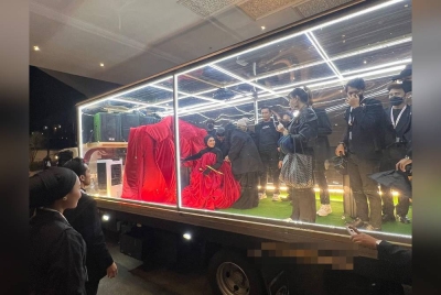 Aina hadir menaiki lori lut sinar dan turun di hadapan pintu utama dengan mengenakan blazer saiz gergasi berona merah. - Foto TV3