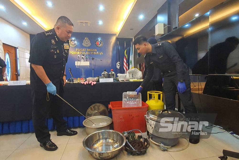 Kok Chin (kiri) menunjukkan peralatan memproses dadah yang dirampas di sebuah rumah di kawasan Bandar Bahru.