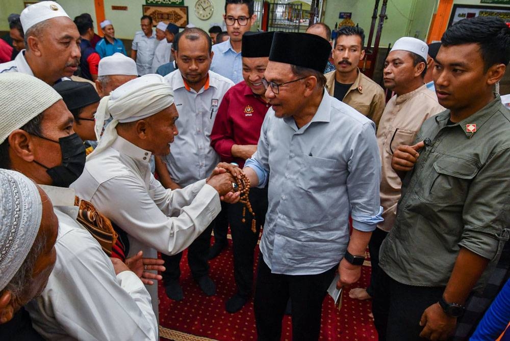 Anwar (tiga dari kanan) bersalaman dengan para jemaah selepas selesai menunaikan solat zohor sewaktu hadir pada Program Sentuhan MADANI Felda Daerah Gua Musang di Masjid Al-Ghufran, Chiku 5/6 pada Ahad. - Foto: Bernama