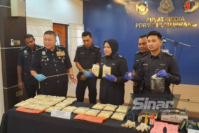 Kok Chin (kiri) menunjukkan dadah jenis heroin yang dirampas daripada dua suspek.