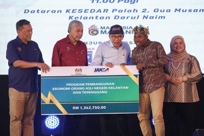 Anwar (tengah) menyerahkan sumbangan bagi Program Pembangunan Orang Asli Negeri Kelantan dah Terengganu kepada wakil Jabatan Kemajuan Orang Asli (Jakoa), Mohd Fazli Mamok (dua dari kanan) pada Program Sentuhan Kasih Desa Kelantan di Dataran Kesedar Paloh 2 pada Ahad. - Foto Bernama