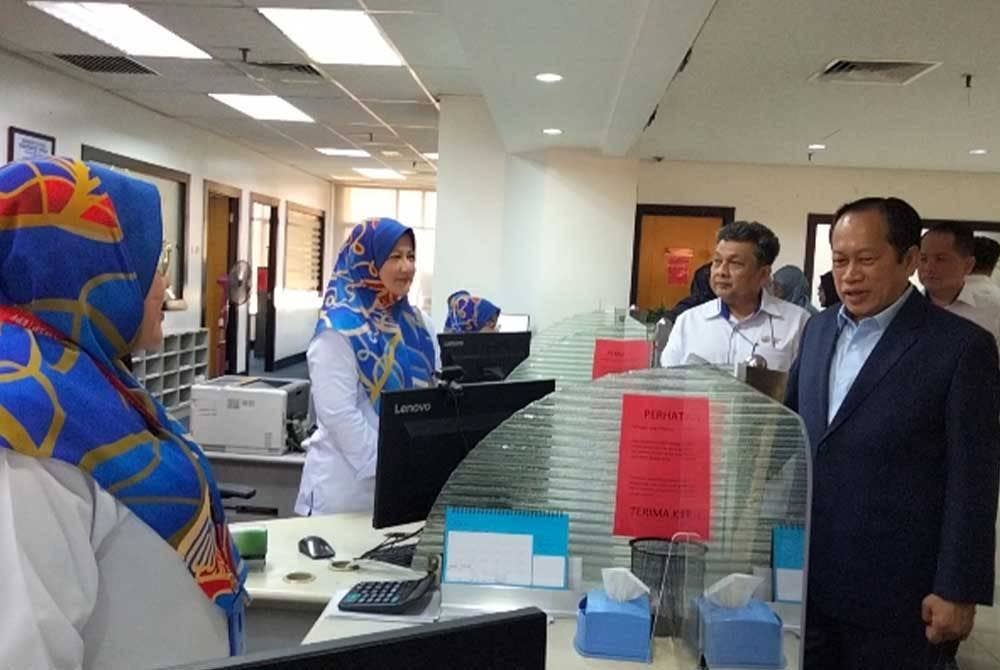 Ahmad (kanan) bertanya khabar kakitangan di kaunter KWSP pada Isnin.