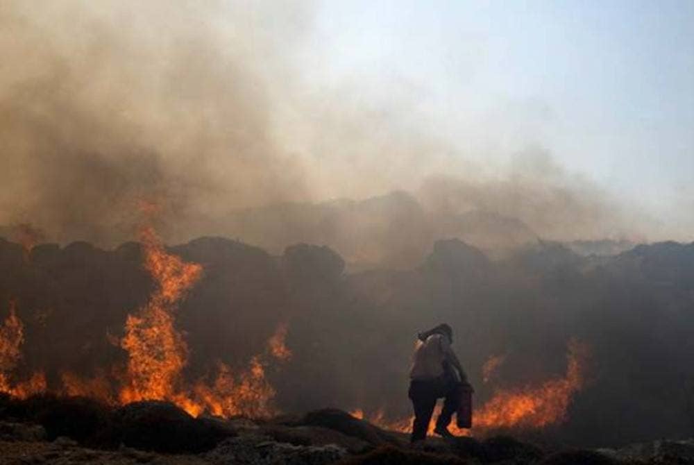 Seorang lelaki cuba memadamkan kebakaran yang tercetus di Lindos, Greece. - Foto AP